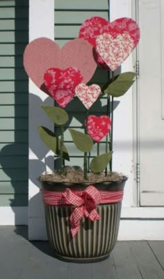 a potted plant with paper hearts in it sitting on the side of a house