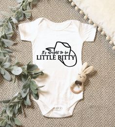 a baby's bodysuit with the words, your design here is surrounded by greenery