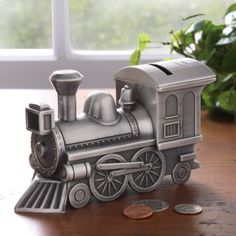 a toy train sitting on top of a wooden table next to a potted plant