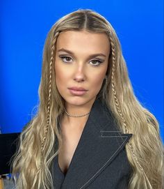 a woman with long blonde hair and braids on her head is posing for a photo