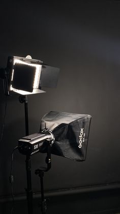 a light that is sitting on top of a tripod in the dark with a bag next to it