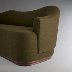 a green chair sitting on top of a white floor next to a wooden frame and wall