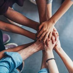 several people holding hands in the middle of a circle with their hands together on top of each other