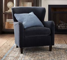 a living room with a chair, rug and fireplace