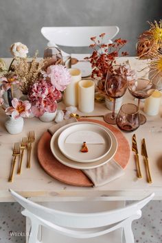 the table is set with flowers, candles and place settings for an elegant dinner party