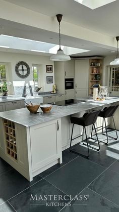 a large kitchen with an island in the middle and two stools at the end