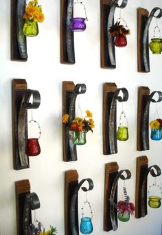 the wall is decorated with many different vases and hanging on metal brackets that hold flowers