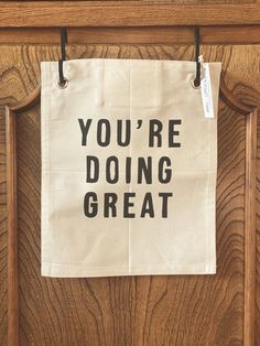 a tea towel that says you're doing great hanging on a wooden door frame