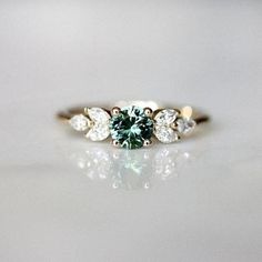 a green diamond ring with three pear shaped diamonds