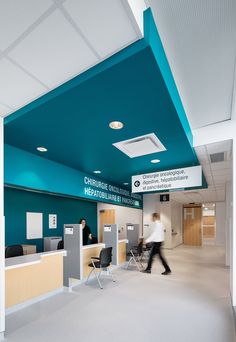 a man walking through an office lobby with blue and white ceiling tiles on the walls