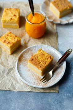 there are four pieces of cake on the plate next to an orange and a fork