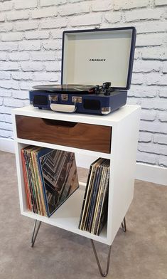 an old record player is sitting on top of a white shelf with records in it