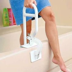 a woman in blue dress sitting on a white step stool next to a bath tub