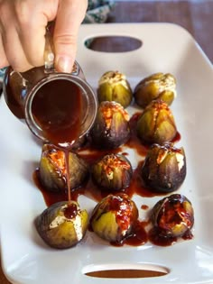 someone is dipping something into some food on a white platter with red sauce in the middle