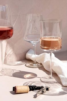 three wine glasses sitting on top of a table next to a bottle and corkscrew