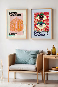 two framed posters hang on the wall above a couch in a room with white walls