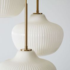 two white lamps hanging from the ceiling with gold accents on each lamp rod and one light bulb