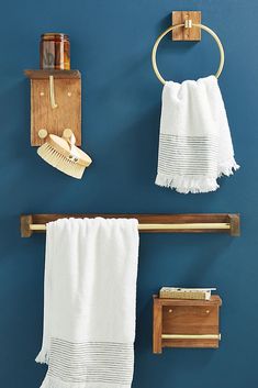 two towels hanging on the wall next to a towel rack and shelf with hairbrushes