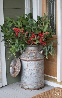 an old metal can with flowers in it sitting on the front porch next to a door