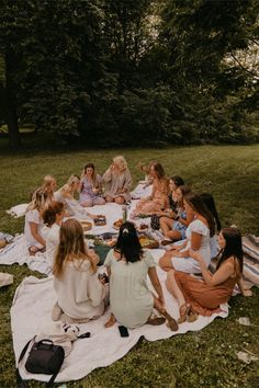 a group of women sitting on top of a grass covered field next to each other