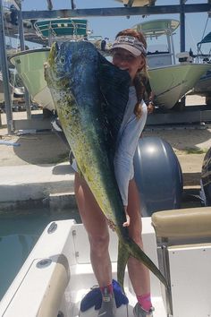 a woman holding a large fish on a boat