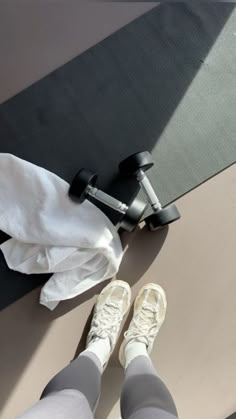 a pair of feet with white socks and running shoes next to a black exercise mat