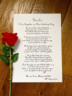 a red rose sitting on top of a piece of paper next to a poem written in cursive writing