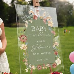 a baby shower sign sitting on top of a lush green field