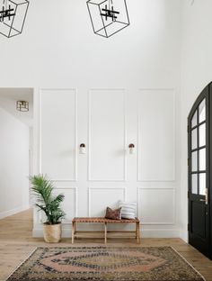 a living room with white walls and wooden floors, an area rug and two hanging lights