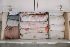 an open drawer with folded towels and blankets in it on top of carpeted flooring