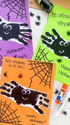 four halloween cards with handprints on them and spider web in the middle one