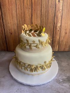 a three tiered cake with gold leaves on top