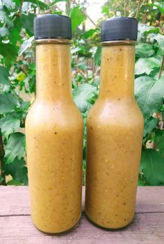 two bottles filled with mustard sitting on top of a wooden table