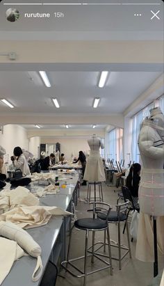 a room filled with lots of mannequins and tables covered in white cloth