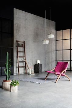 an empty room with a chair, potted plant and ladder on the floor in front of it