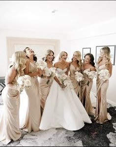 a group of women standing next to each other in front of a mirror holding bouquets