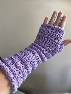 a hand that is wearing a purple crocheted arm warmer