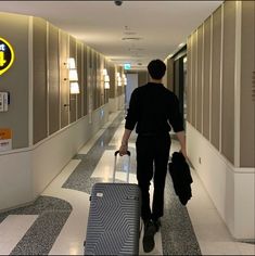 a man is walking down the hallway with his luggage