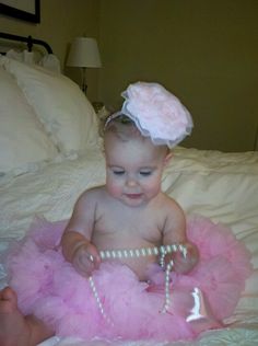 a baby sitting on top of a bed wearing a pink tutu