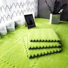 three green rugs on top of a floor next to a potted plant and photo frame