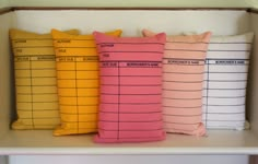 four pillows sitting on top of a shelf in front of a bookcase with numbers