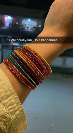 a person is holding their arm with several different colored bracelets on it's wrist