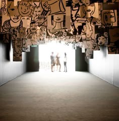 two people standing in an open doorway with many cartoon drawings on the wall above them