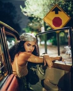 a woman leaning out the window of a car with her hand on the door handle