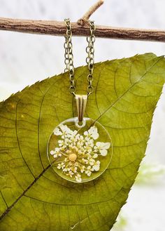 This beautiful floral mustard seed necklace is perfect for any occasion!  Share your faith and your love of nature everywhere you go. This beautiful handmade resin necklace makes the perfect gift for a loved one, a best friend, or just a reminder of your own inner beauty and faith.  Necklace is handmade with resin, real flowers, mustard seeds, and an antique bronze chain.  Chain Length: 18 inches long  Chain Width: 1.5 mm Antique Bronze chain with lobster clasp Please contact me if you have any questions or requests. Due to the handmade nature of the resin process no two necklaces will ever be exactly identical. Please keep in mind that there may be some minor imperfections in the resin, such as tiny air bubbles SHOP DESCRIPTION: Resin jewelry has endless possibilities and I love creating Spiritual Style Necklace With Pressed Flowers As A Gift, Spiritual Necklaces With Pressed Flowers As Gift, Yellow Necklace With Birth Flower Pendant, Yellow Birth Flower Pendant Necklace, Gold Nature-inspired Flower Necklace For Gift, Nature-inspired Gold Flower Necklace For Gift, Botanical Style Gold Resin Jewelry, Resin Necklace With Flower Pendant For Birth Flower, Resin Birth Flower Pendant Necklace