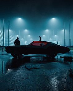 two people standing in front of a car at night