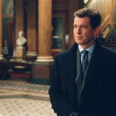 a man in a suit and tie standing in front of a pillared room with columns