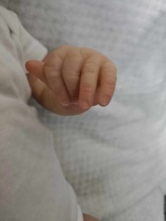 a close up of a person holding a baby's hand in their left hand