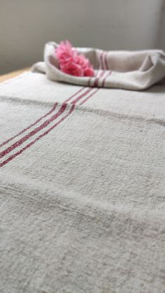 a white table cloth with red lines on it and a pink flower in the middle