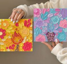 two women holding up colorful cards with designs on them, one has a cat and the other is a bird